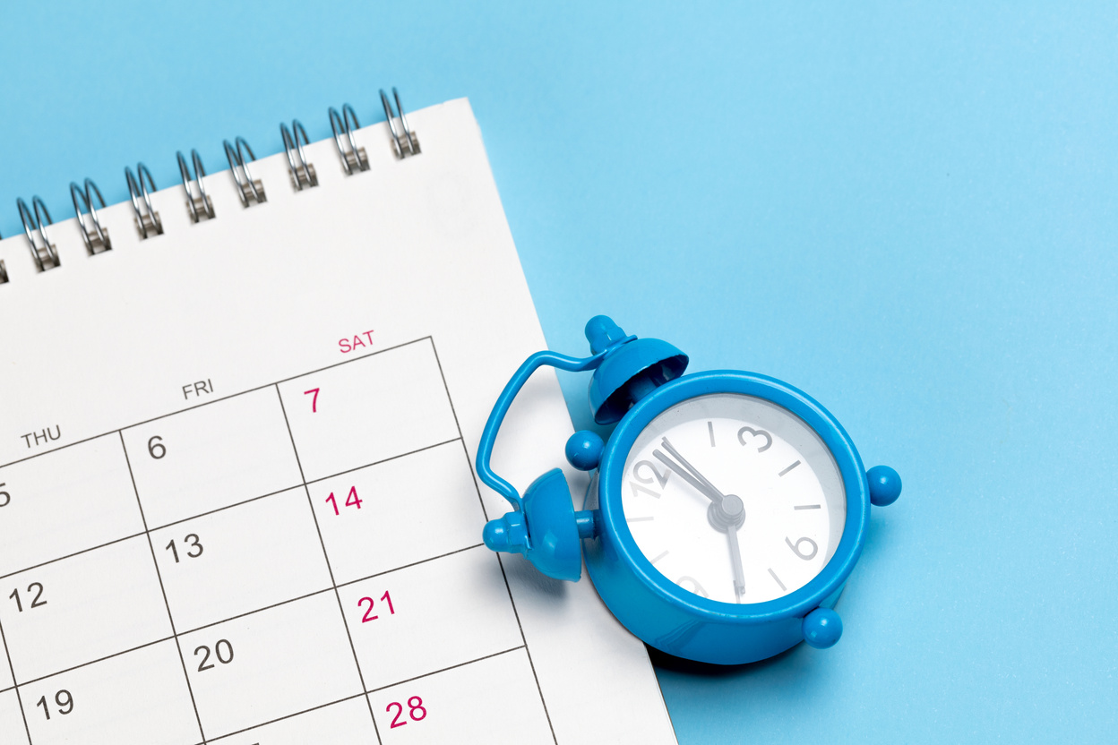 Alarm Clock and Calendar on a Blue Background 